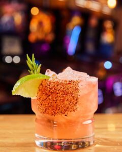 A pink drink with salt on the rim and a lime