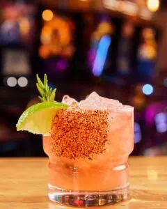 A pink drink with salt on the rim and a lime