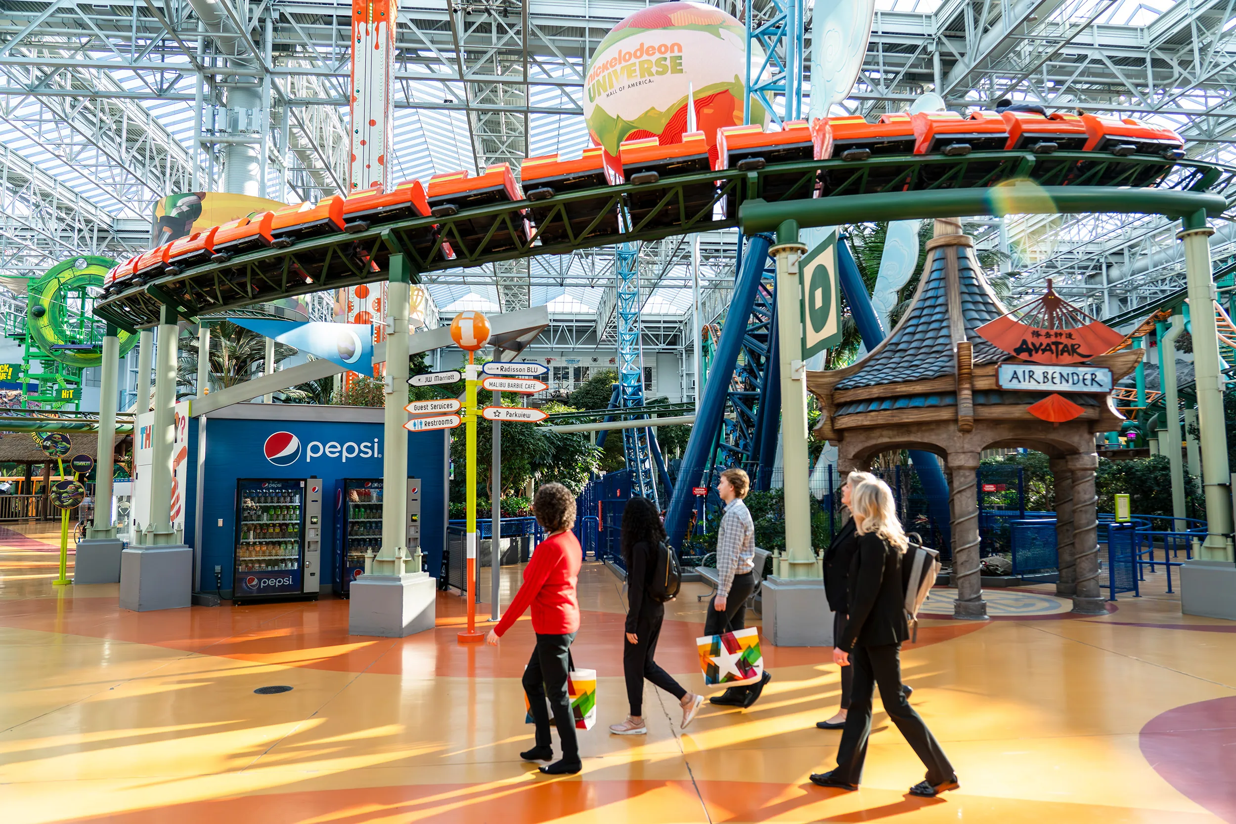 A group walking under a roller coaster in Nickelodeon Universe