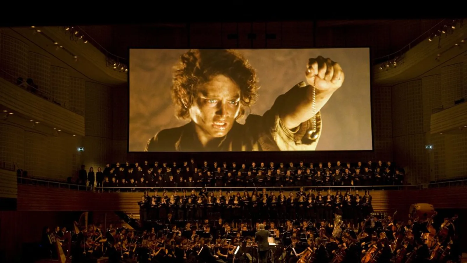 The Lord of the Rings is projected on a screen behind a singing choir