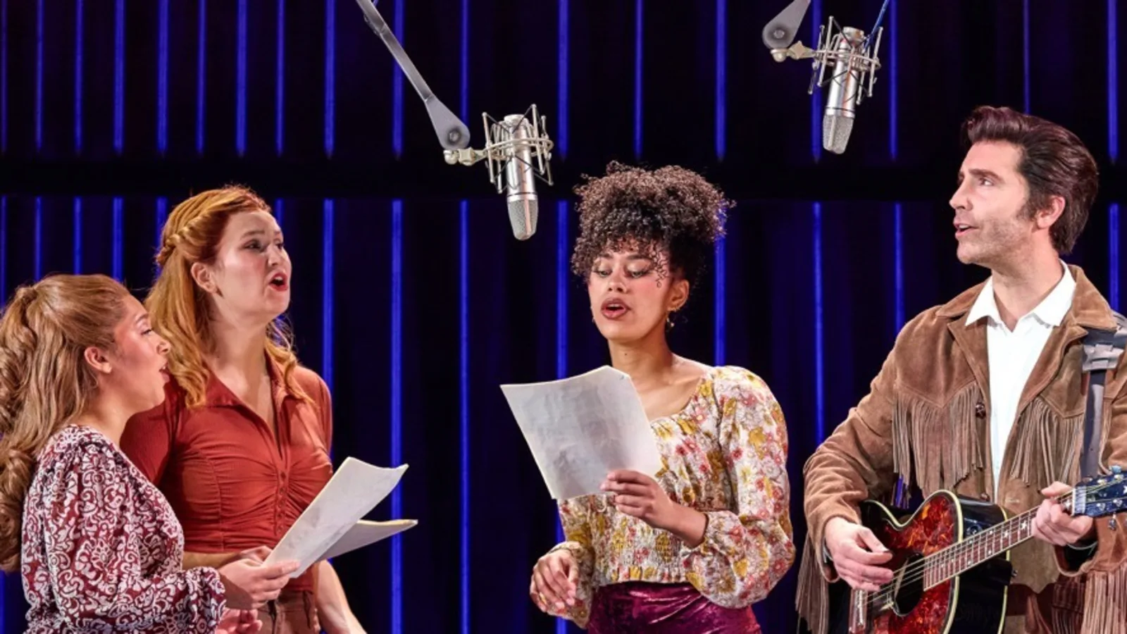 4 people in 1960s attire hold scripts and sing into microphones