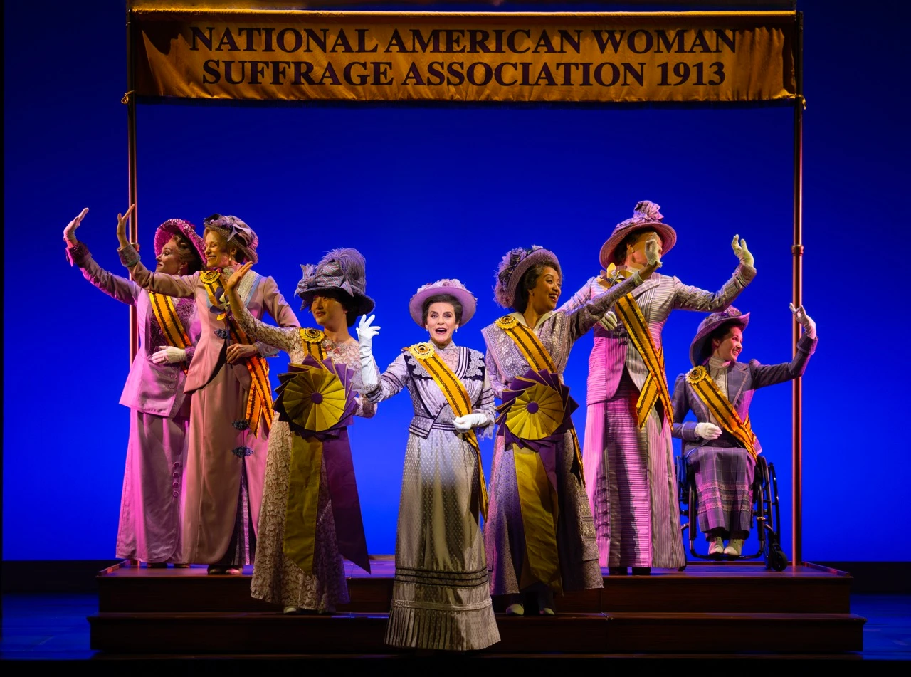 Suffragettes perform in front of a sign that reads National American Woman Suffrage Association 1913