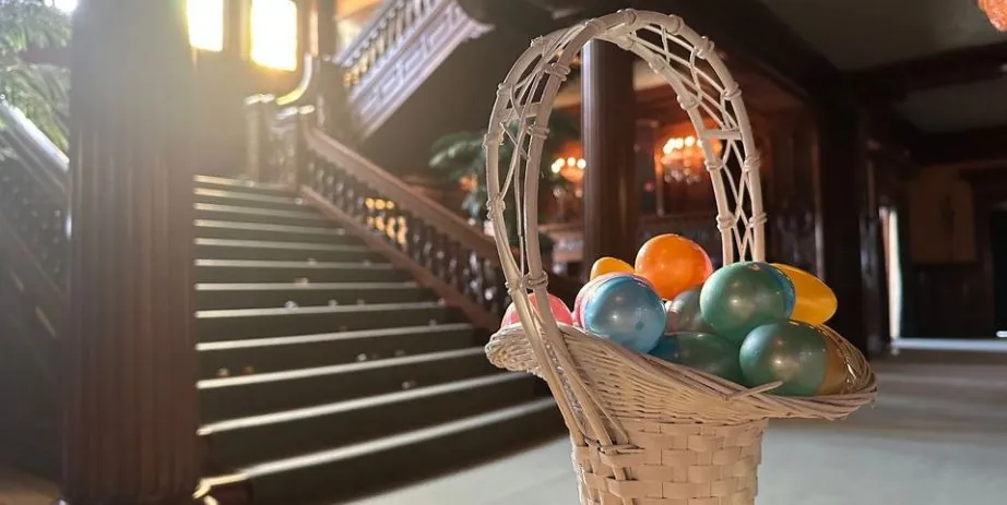 An Easter basket full of plastic Easter eggs sits in front of a staircase in the James J Hill House