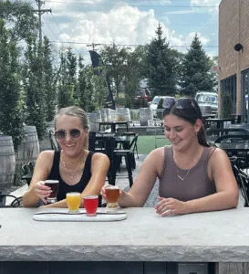 Two women sampling from a beer flight