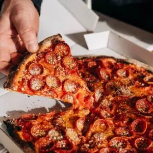 Pepperoni pizza in a box with one slice being pulled out.