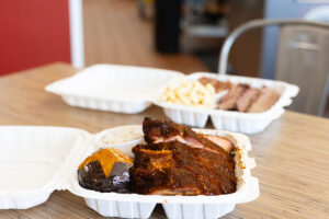Two takeout containers filled with barbecued meat