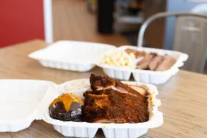 Two takeout containers filled with barbecued meat