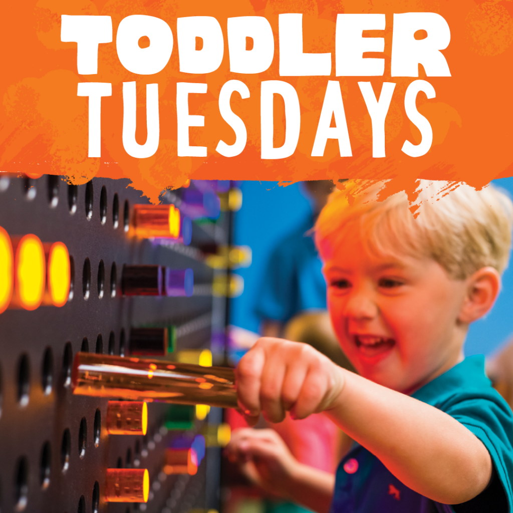 A toddler pulls a large lite brite out of a hole