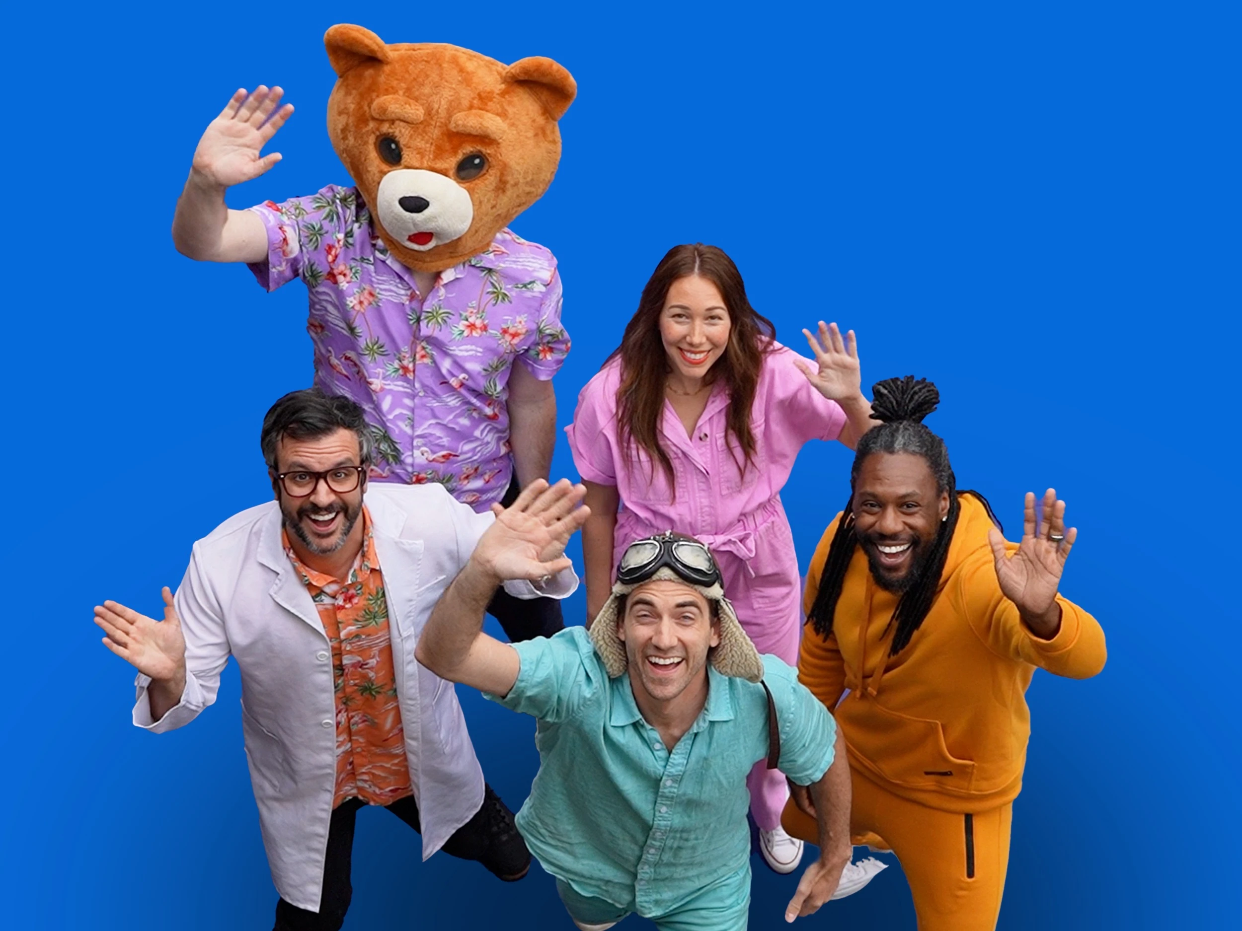 A group of people dressed in bright colors wave at the camera