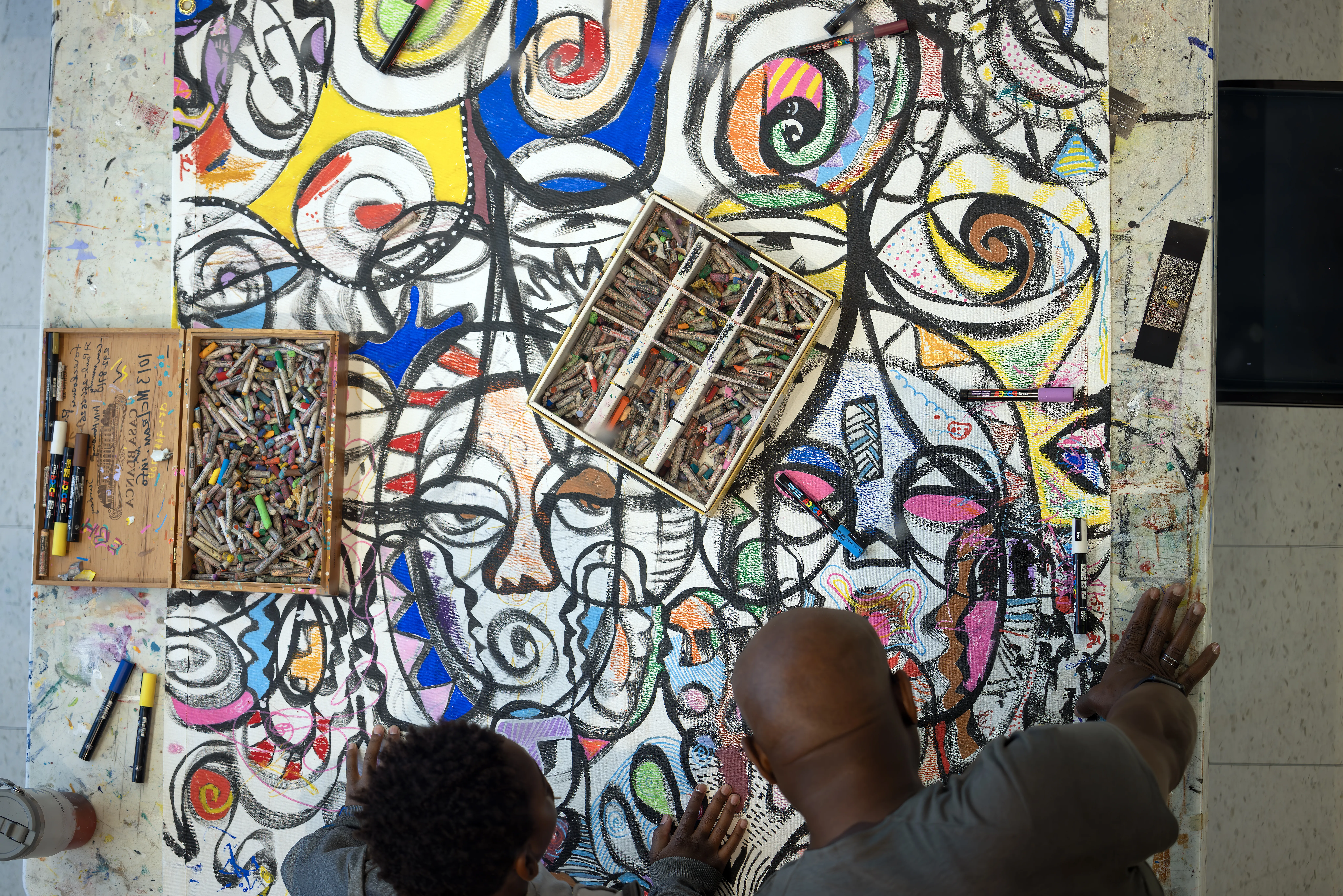 Two people draw on a mural
