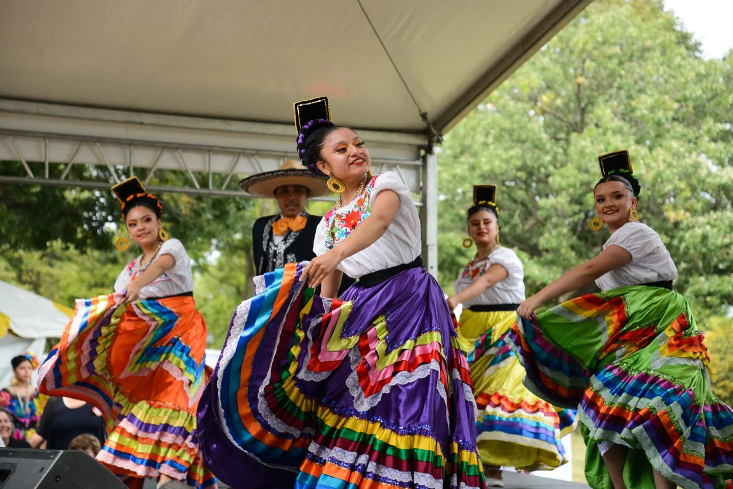 Women in traditional Mexican attire dance on stage