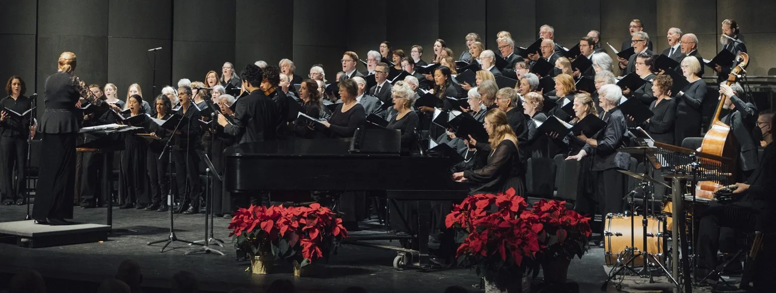 A choral group dressed in black holds binders while singing