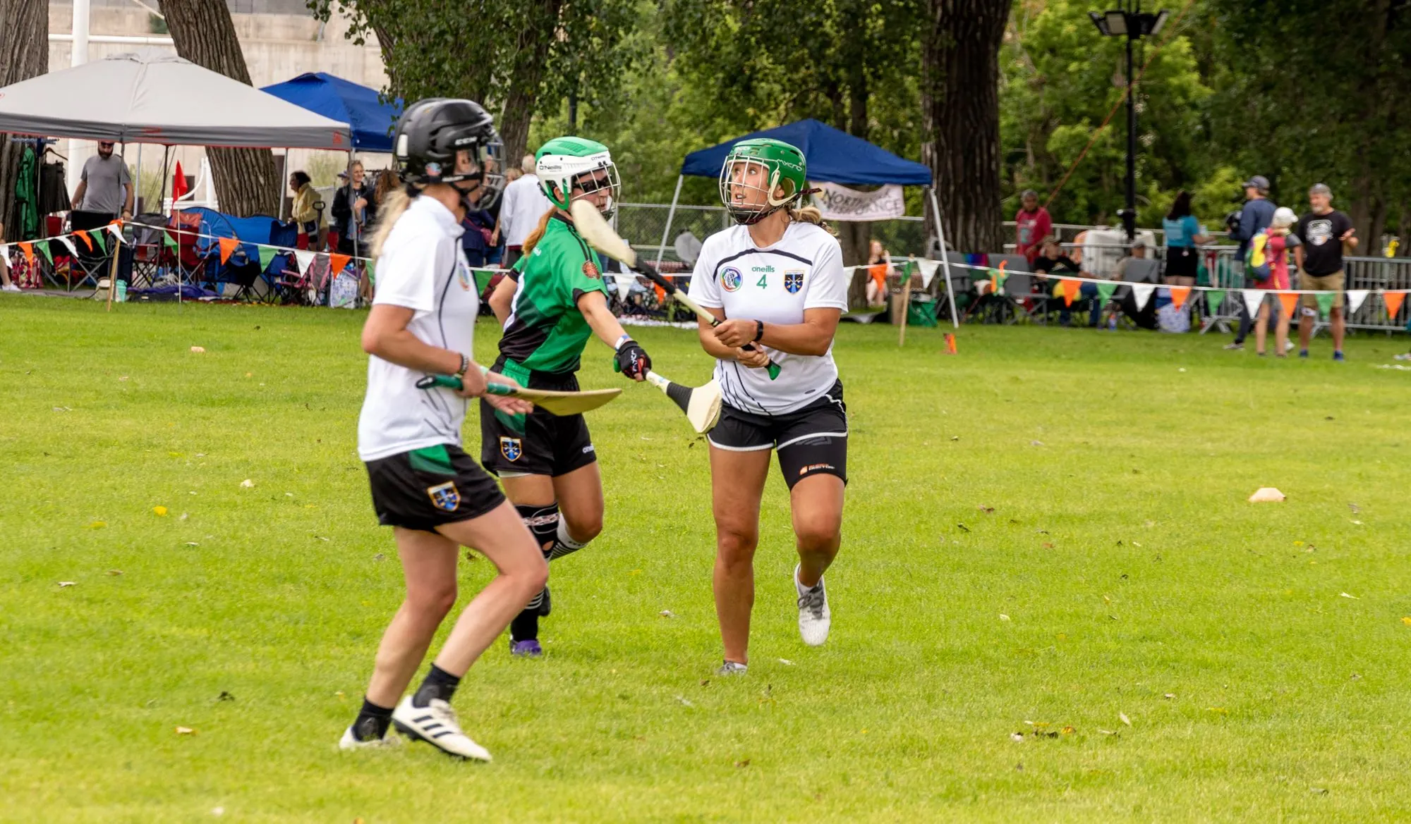 3 women in Irish jerseys compete in a lacrosse game