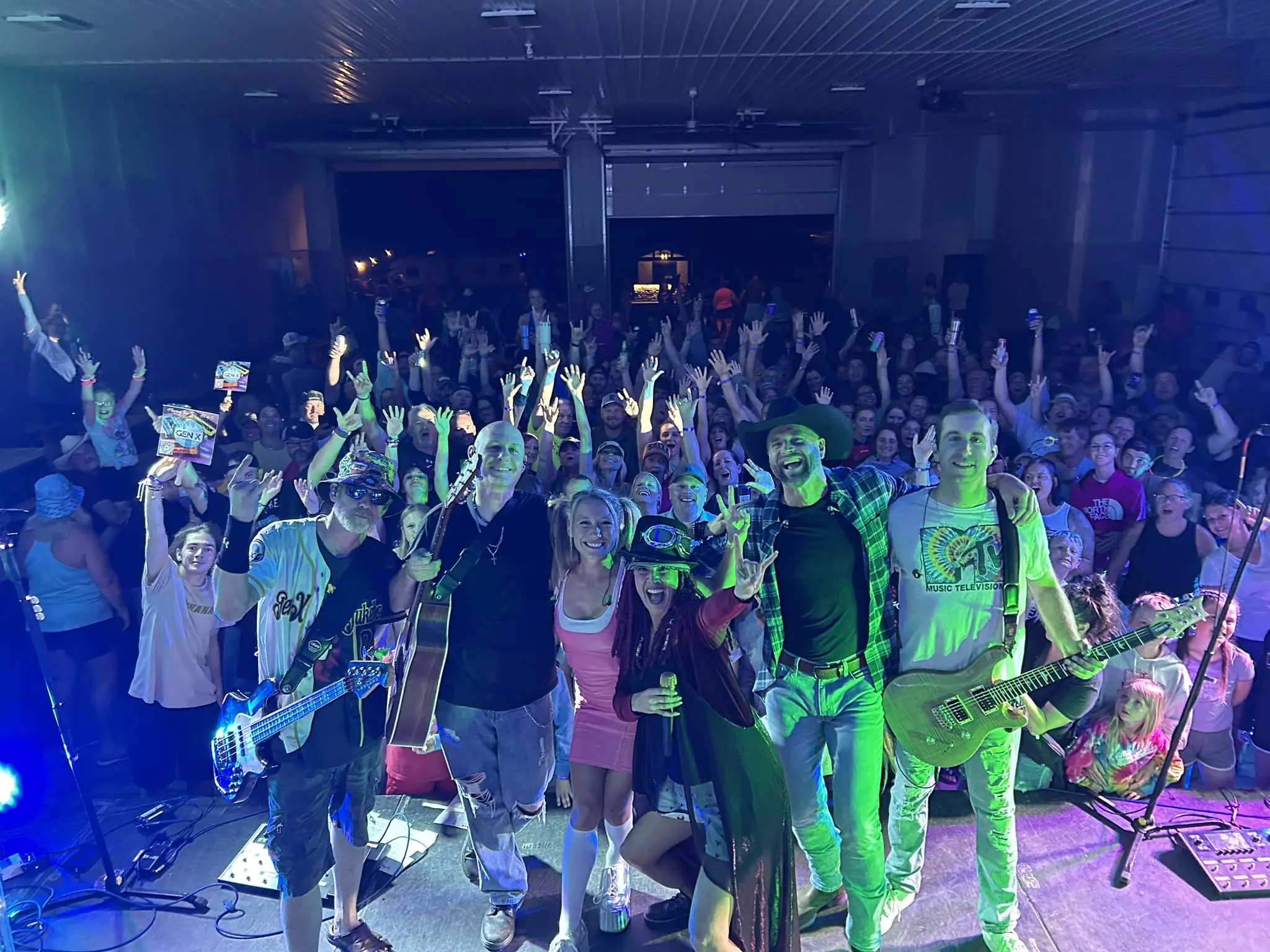 A band poses on stage with their fans in the background