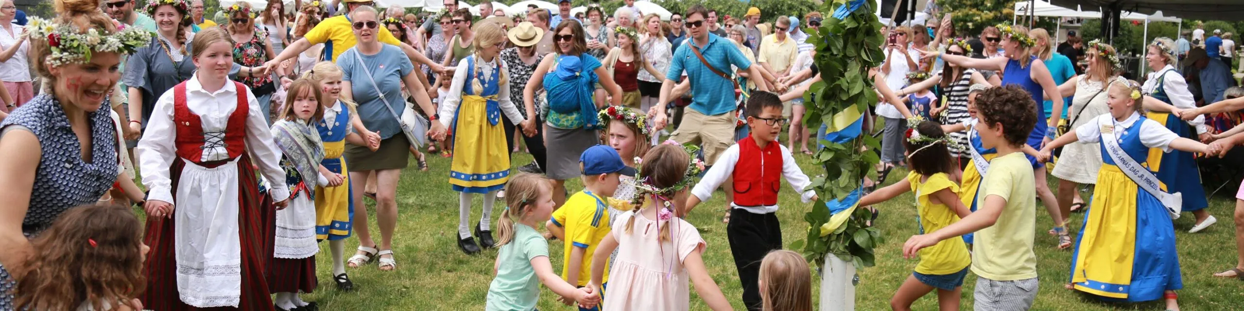 A group of children in Swedish outfits dancing while holding hands