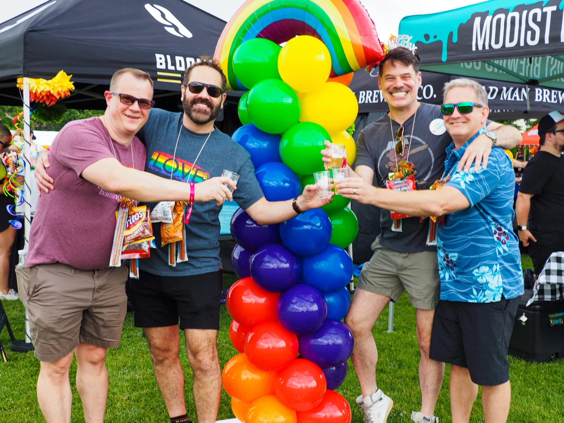 4 men cheersing beer samples in front of a balloon tower
