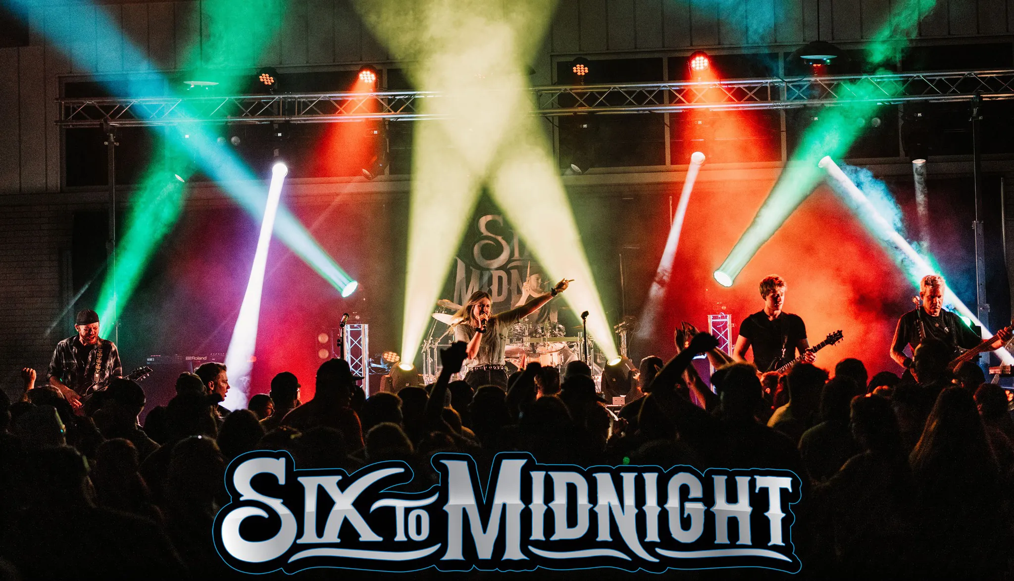 A rock band performs with multicolored lights shining behind them