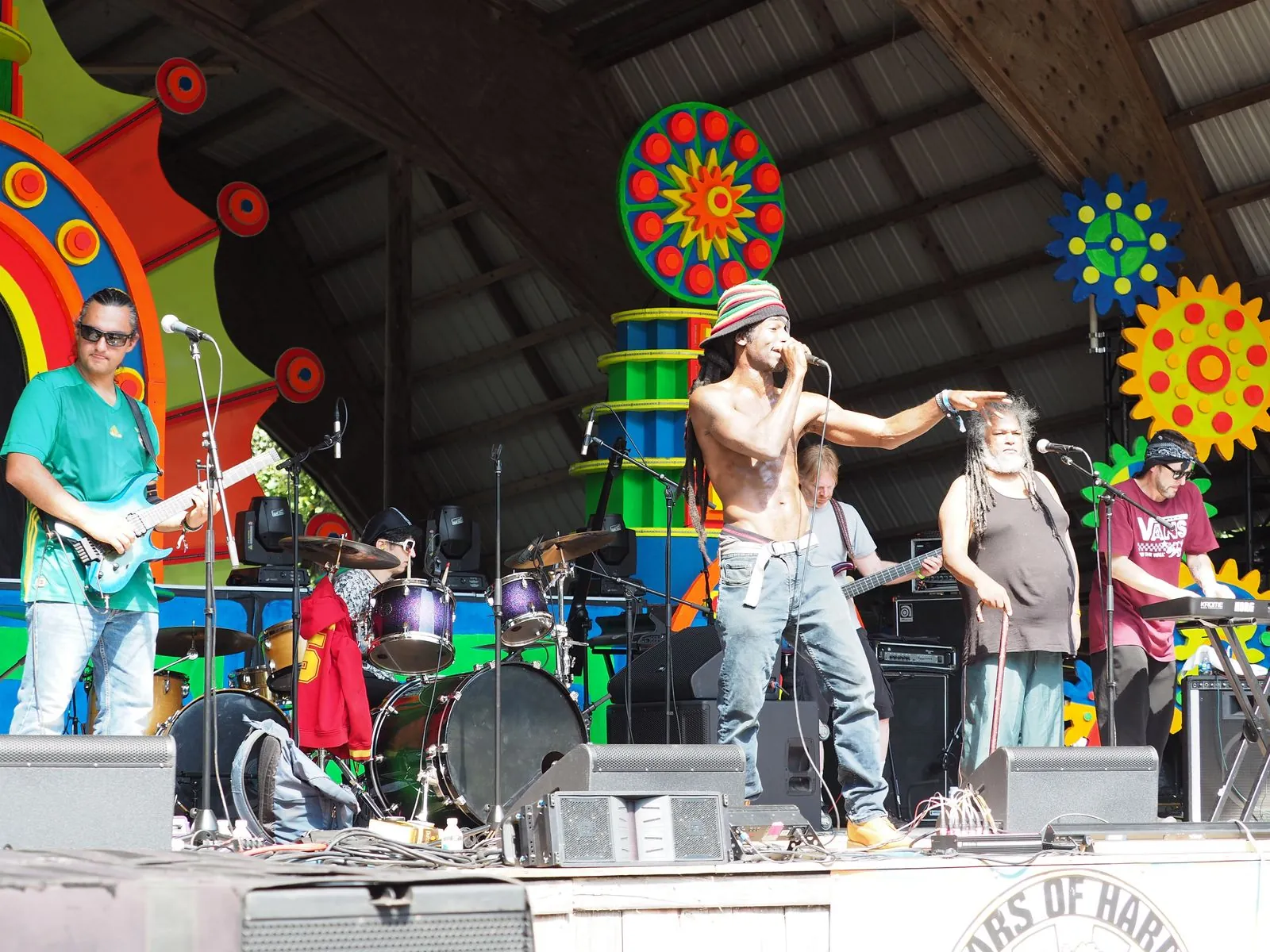 A reggae band performs with multicolored stage props behind them