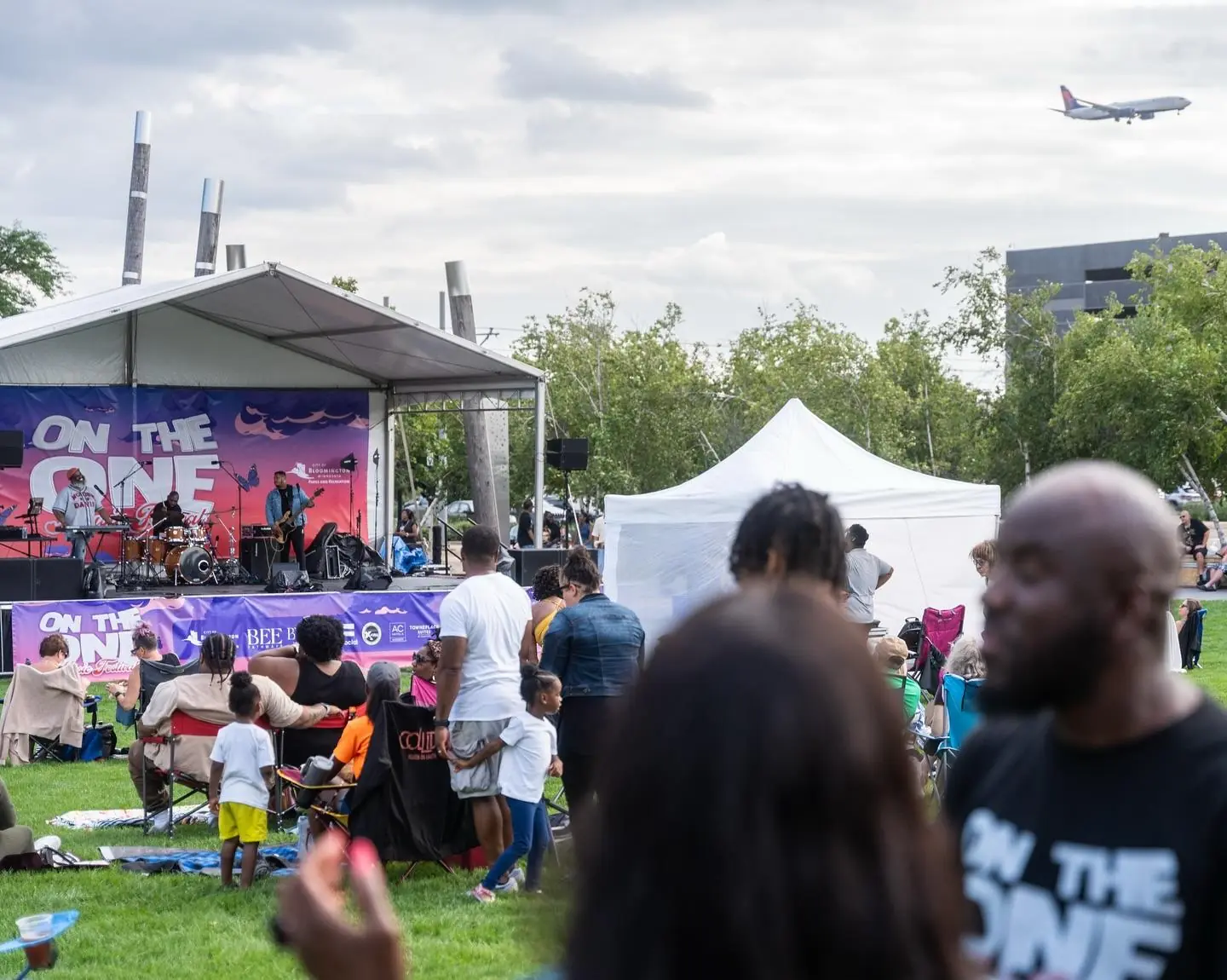 A crowd of people watching performers on stage at On The One Music Festival.